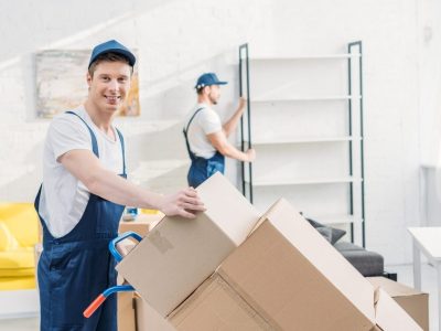 imgi_211_two-movers-in-uniform-transporting-cardboard-boxes-and-furniture-in-apartment-e1670221445352